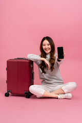 Beautiful asian female passenger showing her smart phone. Portrait of a smiling girl in sweater with suitcase in full length size. Winter lifestyle and travel concept - 644343556