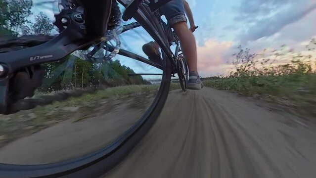 Cyclists ride cross-country mountain bicycles along sandy field path at sunset. MTB bikes trip journey. Jockey wheels, rear derailleur. Action camera shot with wide angle lens visual distortion
