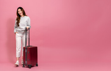 Beautiful asian female passenger in sweater, jeans, and luggage. Portrait of a smiling girl with luggage in full length size. Winter lifestyle and travel concept - 644344163