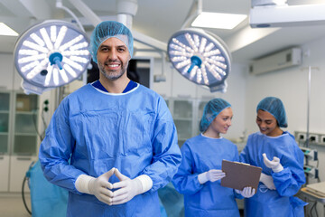 Portrait of male surgeon standing with arms crossed in operation theater at hospital. Team surgeons...