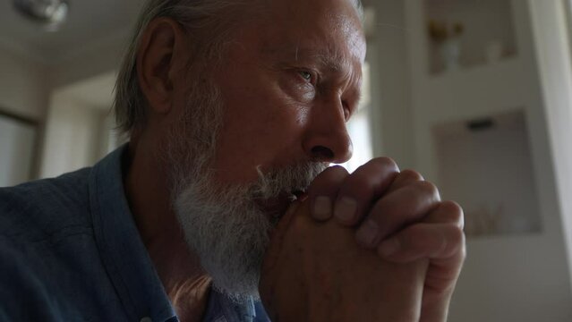 Closeup low-angle view of depressed mature hoary man crying, feeling desperate, mourning alone at home, having psychological problems. Dementia alzheimer mental senile disease, loneliness concept.