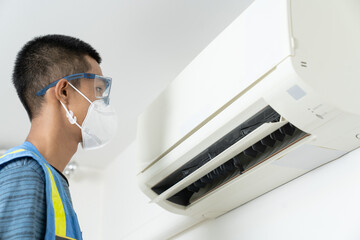 Professional male staff cleaning, air conditioning, inspection and maintenance for good hygiene and...