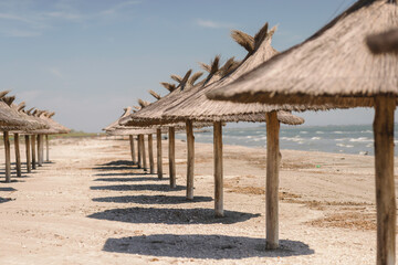 Photo of straw umbrellas creating a colorful row on a beautiful sandy beach with the sparkling...