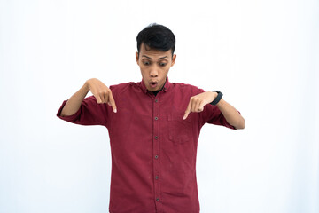 Asian man, businessman or student concept wearing red casual shirt pointing down copy space with happy or surprised expression. Isolated white background.