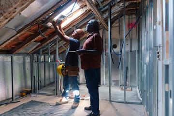 Architect and builder holding solar panel in front of window at site
