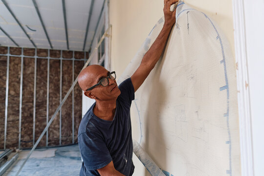 Mature construction worker with mesh sheet on wall at site