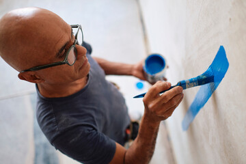 Construction worker painting wall with brush at site