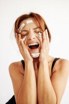 Frustrated woman with broken mirror pieces on face screaming