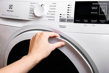 Female hand open the door in washing machine.