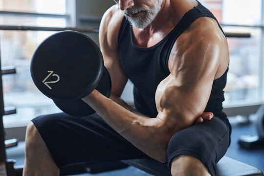 Man with dumbbell strengthening biceps in gym