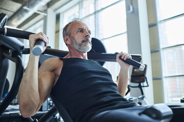 Contemplative man doing strengthening exercise in health club