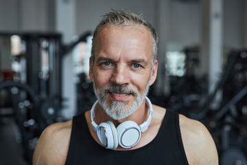 Smiling mature man with headphones in health club