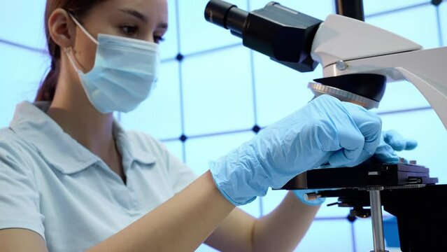 female laboratory assistant working with microscope in university laboratory
