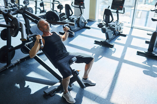 Mature man doing strength training exercise in gym