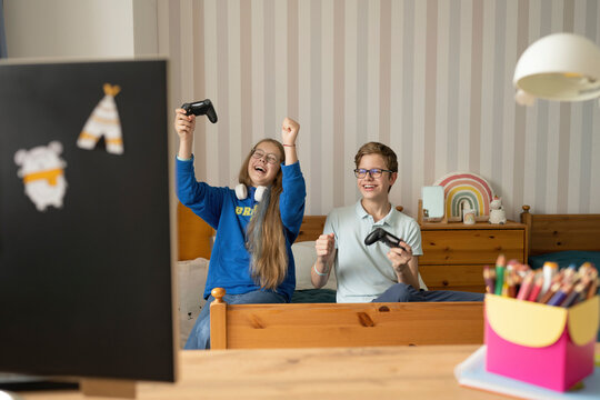 Happy friends with joysticks celebrates winning video game at home