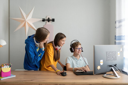 Smiling boy playing video game on computer by friends at home