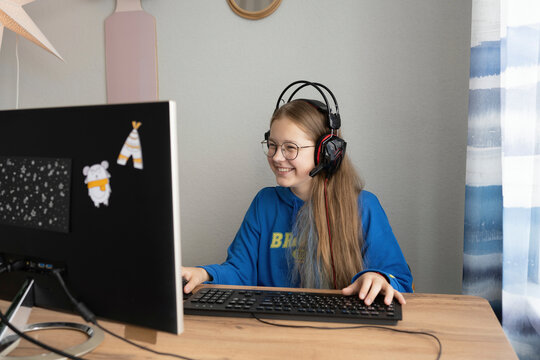 Happy brunette girl playing computer game at table