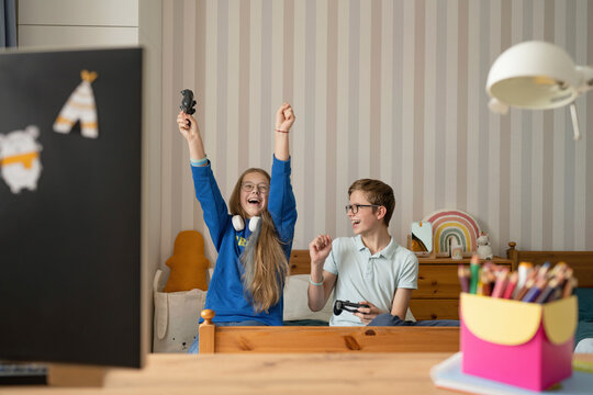 Cheerful girl celebrates winning video game with friend at home