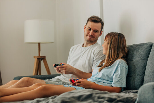Smiling bother and sister playing video game on bed at home