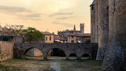 Old romanic bridge and aquaduct connecting to a castle with a church in the back and misterious sky - obrazy, fototapety, plakaty