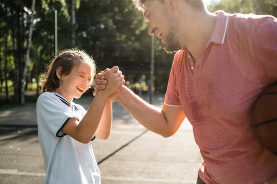 Happy boy holding hands of father in basketball court