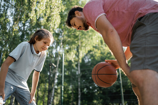 Father teaching son to dribble basketball