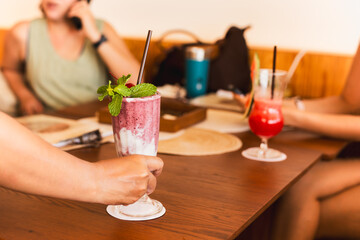 Waiter serving strawberry yogurt smoothie to customer in restaurant.