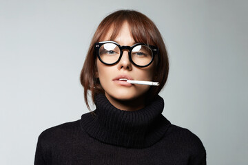 Fototapeta na wymiar beautiful smoking woman in glasses. pretty serious girl with cigarette