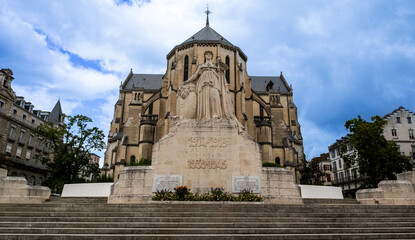 An old statue in front of a church with a clear blue sky