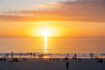 Germany, Schleswig-Holstein, Sun setting over people on sandy beach of Sylt island