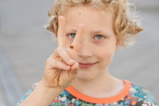 Boy with ladybug gesturing peace sign