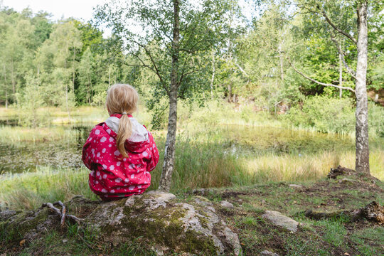 Girl sitting near lake in tranquil forest