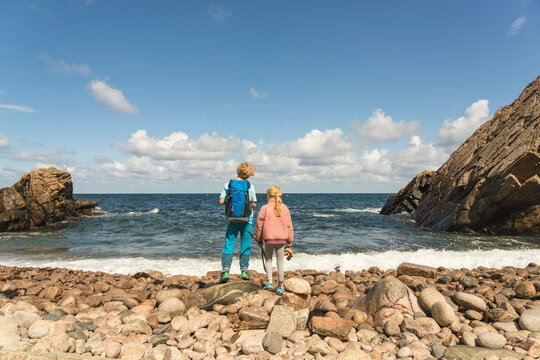 Brother and sister standing on coastline at beach