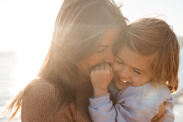 Happy mother carrying daughter at beach on holiday