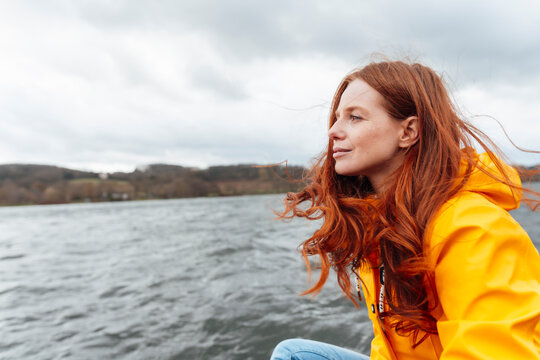 Thoughtful redhead woman looking at lake