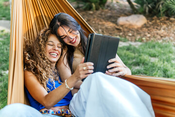 Happy young women using tablet PC in hammock