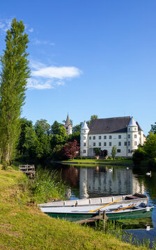 Austria, Upper Austria, Sankt Peter am Hart, Rowboat on bank of Mattig river with Hagenau Castle in background