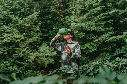 Woman with VR glasses watching trees in forest