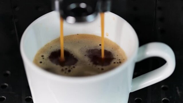 A modern coffee machine pours delicious coffee into a white cup standing on a metal support, close-up. Coffee.