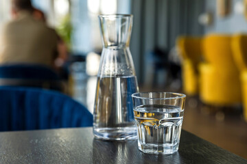 Close-up of glass of water and carafe on table in cafe, coffee shop atmosphere in bokeh background - 644374598