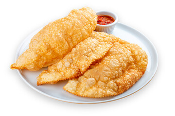 Chebureks with meat, spicy red sauce and greens on a plate. Deep-fried pies made of puff pastry. Isolated image on a white background.