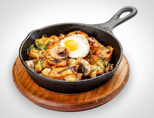 Fried potatoes with wild mushrooms and egg. In a cast iron skillet. Isolated image on white background.