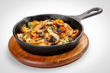 Fried potatoes with wild mushrooms and egg. In a cast iron skillet. Isolated image on white background.