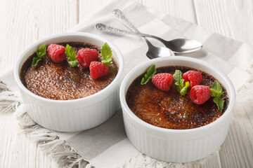 Chocolate creme brulee dessert consisting of a rich custard base topped with a layer of hardened caramelized sugar close-up in a ramekin on the table. Horizontal - obrazy, fototapety, plakaty