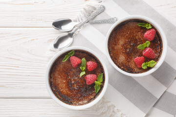 Chocolate creme brulee dessert consisting of a rich custard base topped with a layer of hardened caramelized sugar close-up in a ramekin on the table. Horizontal top view from above