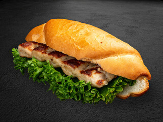 Grilled chicken lula kebabs in a bun with lettuce and sauce. . Isolated on a dark background