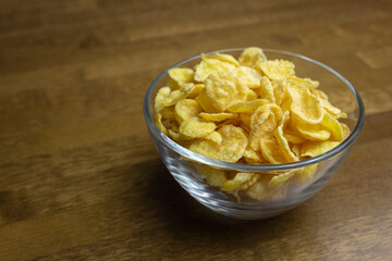 Cornflakes in a glass bowl on a wooden table