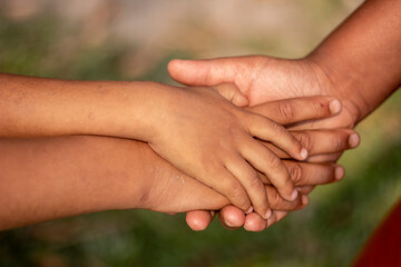 Three boys join hands together and put their hands on each other to form a partnership