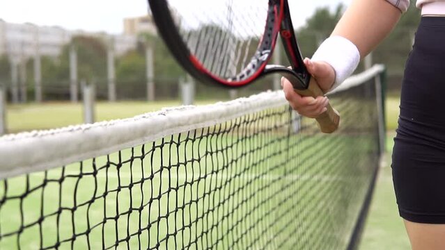 Angry female tennis player hitting a net with racket after losing the match.