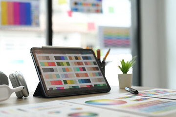 Creative designer, Graphic at workspace with digital tablet, color swatch samples and stationery on wooden table